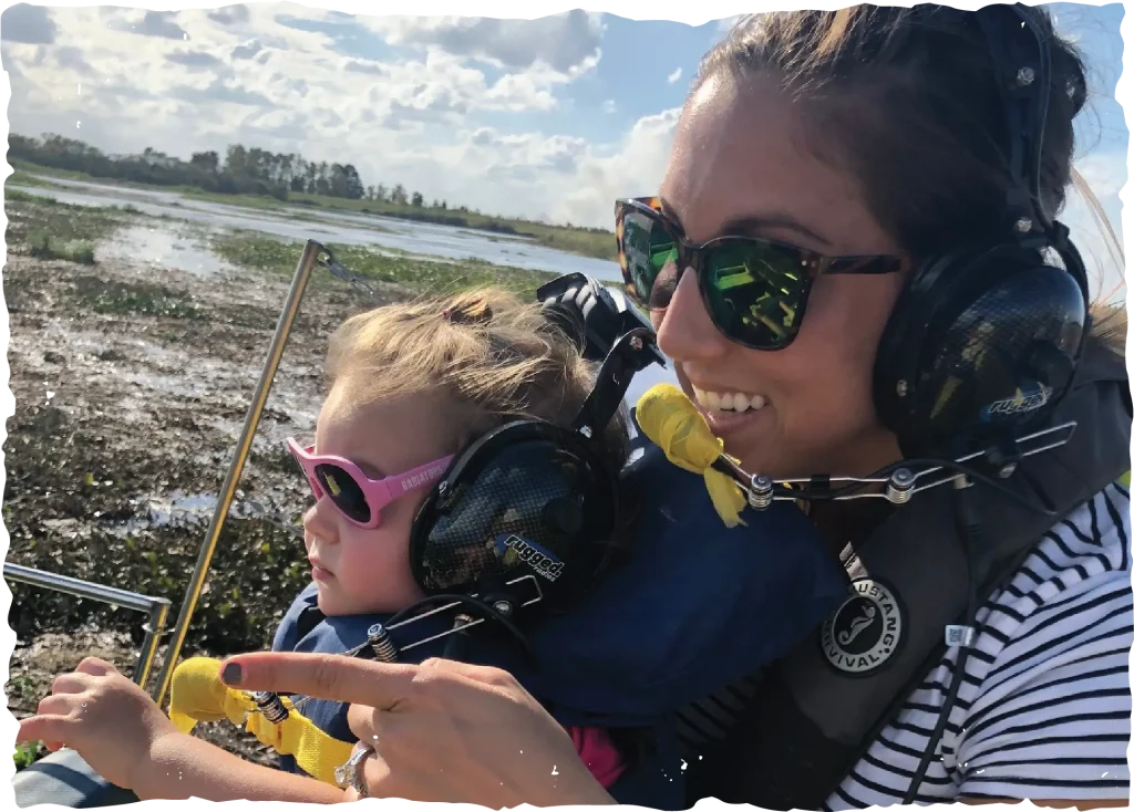 A mother and young daughter wearing headsets and sunglasses during a Vero Beach airboat tour.