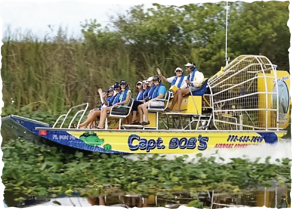 A yellow Captain Bob's airboat full of passengers gliding through the marsh in Vero Beach.